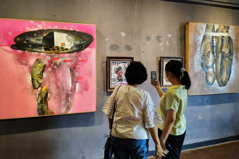 Pengunjung menikmati koleksi pameran lukisan bertema ‘Bermain dan Mempermainkan’ di Galeri Dewan Kesenian Surabaya (foto : Kiki Evelin Olivia Sihaloho | prapanca.id)