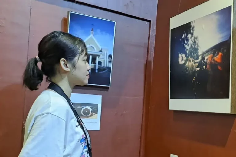Salah satu pengunjung saat melihat hasil foto kamera lubang jarum yang dipamerkan di Pinhole Day 2024 di Galeri Merah Putih, Balai Pemuda Surabaya (foto: Jelita SS | prapanca.id)